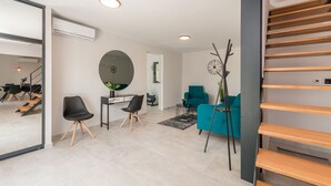A modern living room with a staircase, a round mirror, a teal sofa, and a black chair. - Modern villa BlackWood in Crno, secluded area, near Zadar center, near the beach, private pool, en suite bathrooms (Crno)