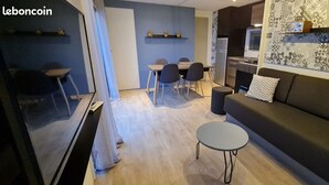 Ett modernt vardagsrum med en soffa, ett runt soffbord och en matplats med stolar och ett bord.