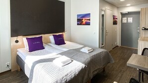 A modern hotel room with a large bed, a desk, and a view of the outside. - Hotelli Loimu (Raisio)