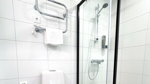 A modern bathroom with a toilet, a glass-enclosed shower, and a towel rack. - Hotelli Loimu (Raisio)