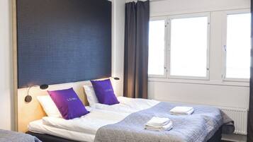 A hotel room with two beds, a desk, and a window with curtains.