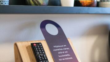 A wooden stand holding a remote control and a hotel tag with text in a foreign language.