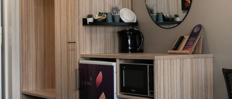 Un dormitorio moderno con cama, armario, kitchenette pequeña y espejo.