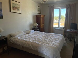 Habitación de hotel con una cama grande, un escritorio con ordenador y una ventana con cortinas.