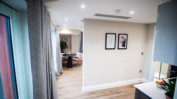 Un interior moderno con suelo de madera, una zona de comedor con mesa y sillas redondas, y dos obras de arte enmarcadas en la pared.