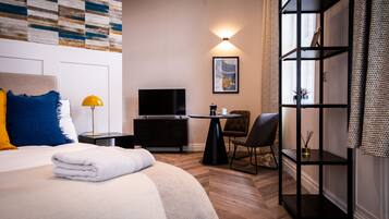 Een hotelkamer met een bed, een televisie, een bureau, een stoel en een boekenkast.