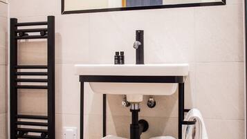 A bathroom with a white sink, black towel rack, and a mirror above the sink.