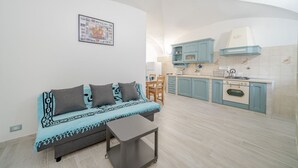 Un espace de vie compact comprenant un canapé, une petite table, un coin cuisine et un espace repas.