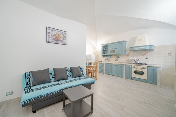 A compact living space with a sofa, a small table, a kitchenette, and a dining area.