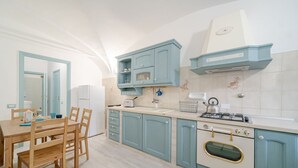 Une cuisine équipée d’une table à manger, de chaises, de placards, d’une cuisinière et d’un évier.