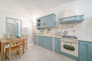 A kitchen with a dining table, chairs, cabinets, a stove, and a sink.
