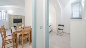 Un salon moderne avec une table à manger, des chaises, un téléviseur et une fenêtre.