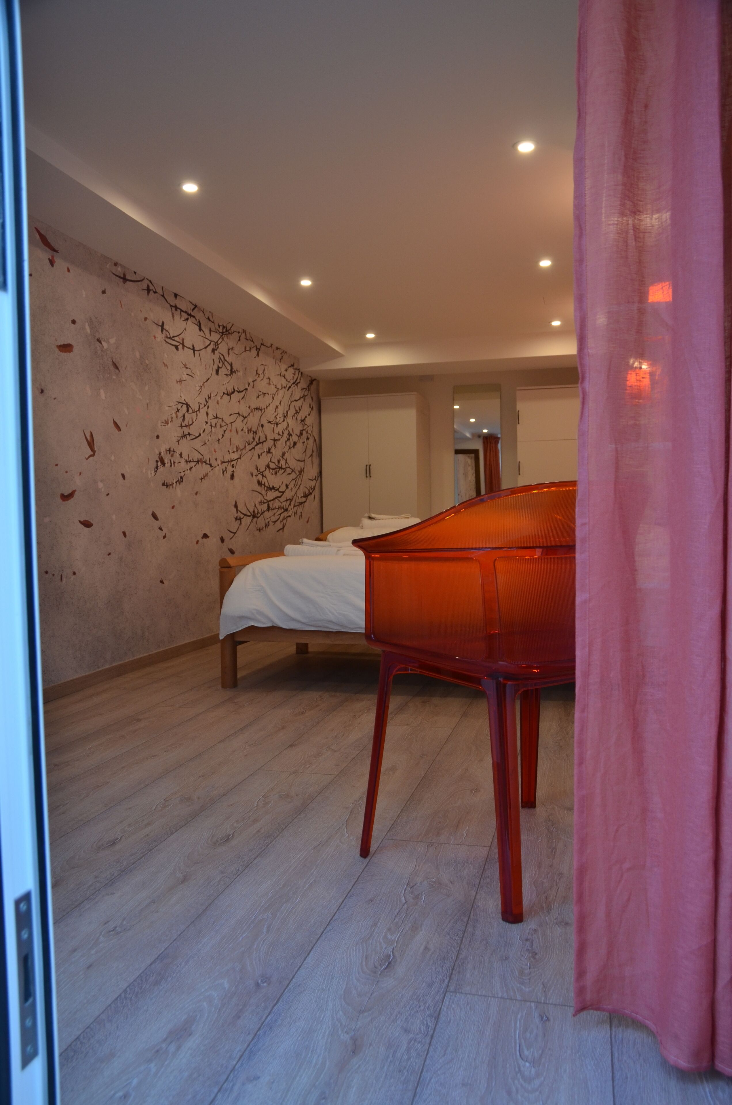 Une chambre à coucher avec un lit, une commode en bois et une chaise rouge.