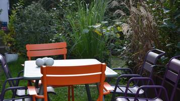 Un espace extérieur aménagé avec une table et des chaises, entouré d’une végétation luxuriante.