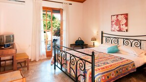Un dormitorio con cama, televisión, una silla y ventana con cortinas.