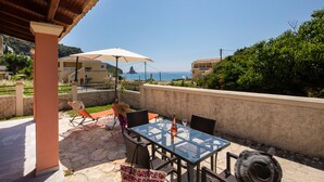 Un patio exterior con una mesa, sillas y una sombrilla.