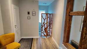 Un interior modern amb un terra de fusta, una cadira groga, una porta blanca i un panell decoratiu.