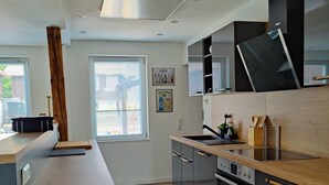 Una cuina moderna amb una illa central, forn integrat i un rellotge a la paret.