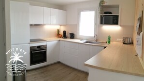 Una cocina moderna con armarios blancos, horno empotrado, microondas y encimera de madera.