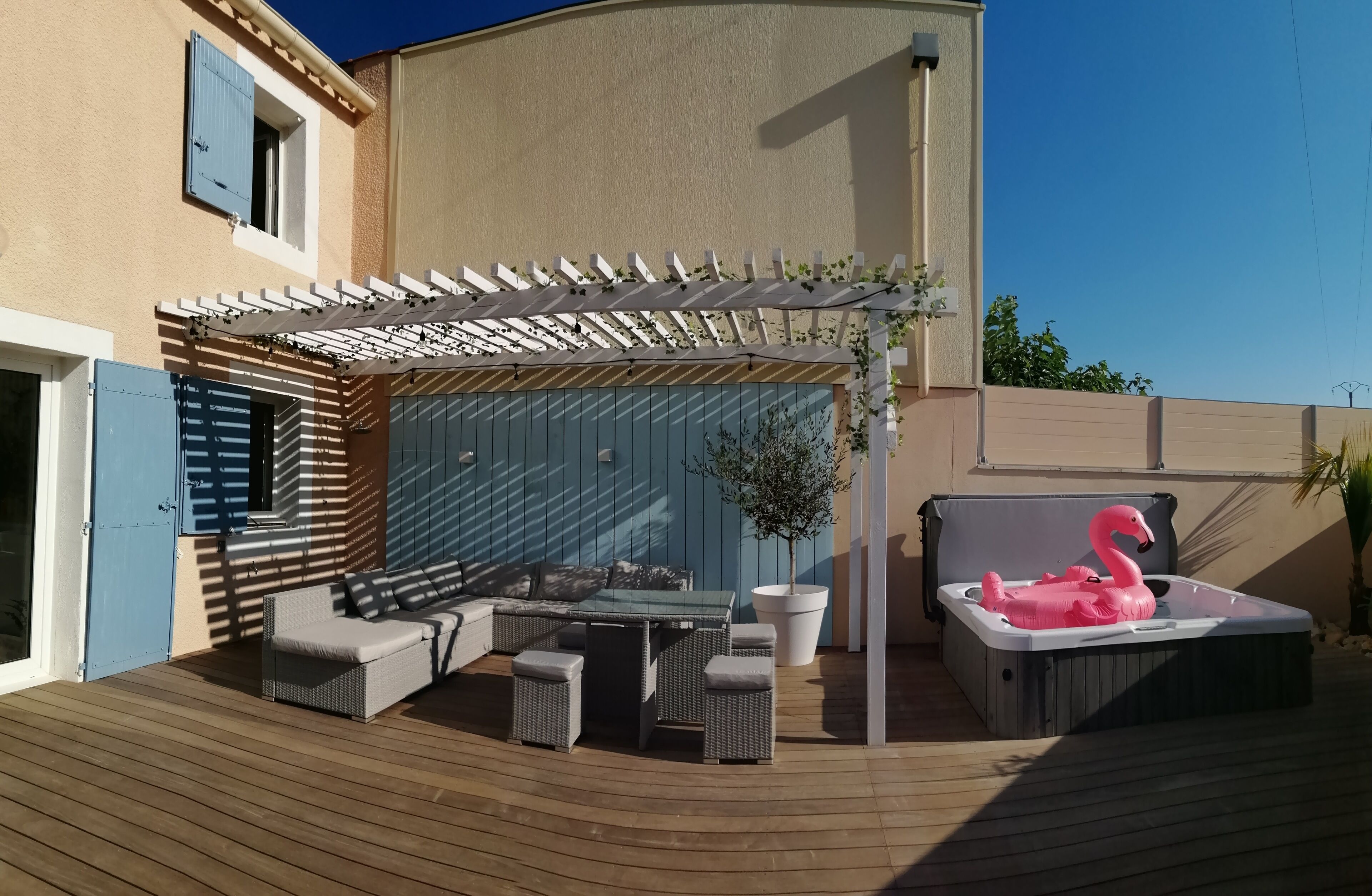 Um pátio externo com área de estar, hidromassagem e pérgola.