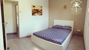 Un dormitorio con cama, una puerta, un cuadro en la pared y un logotipo.