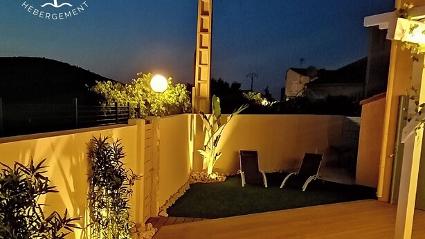 Un jacuzzi con chorros, rodeado de plantas y una terraza de madera.