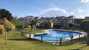 A swimming pool surrounded by a grassy area, with a fence and a lifeguard chair. - El Rinconcito (Rincon de la victoria)