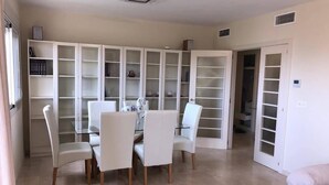 A dining area with a table and chairs, a white cabinet with glass doors, and a door leading to another room. - El Rinconcito (Rincon de la victoria)