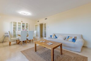 A living room with a sofa, coffee table, and a dining area with chairs and a cabinet. - El Rinconcito (Rincon de la victoria)