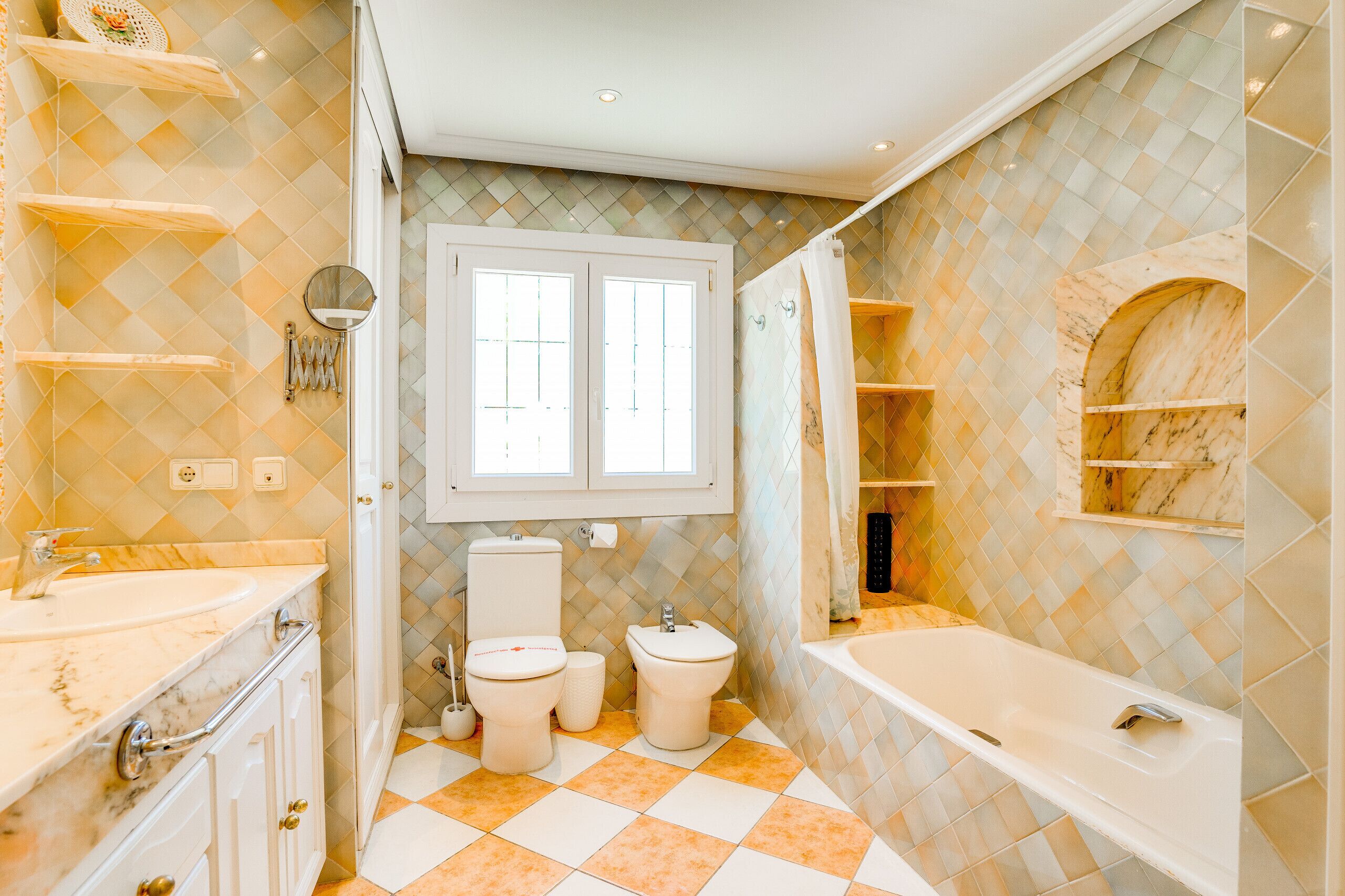 A bathroom with a marble vanity, a bathtub, and a toilet.