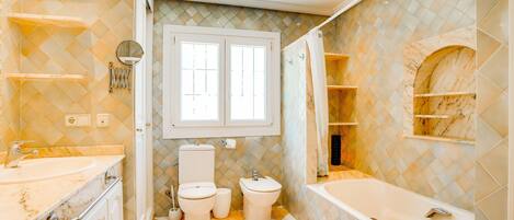 A bathroom with a marble vanity, a bathtub, and a toilet.