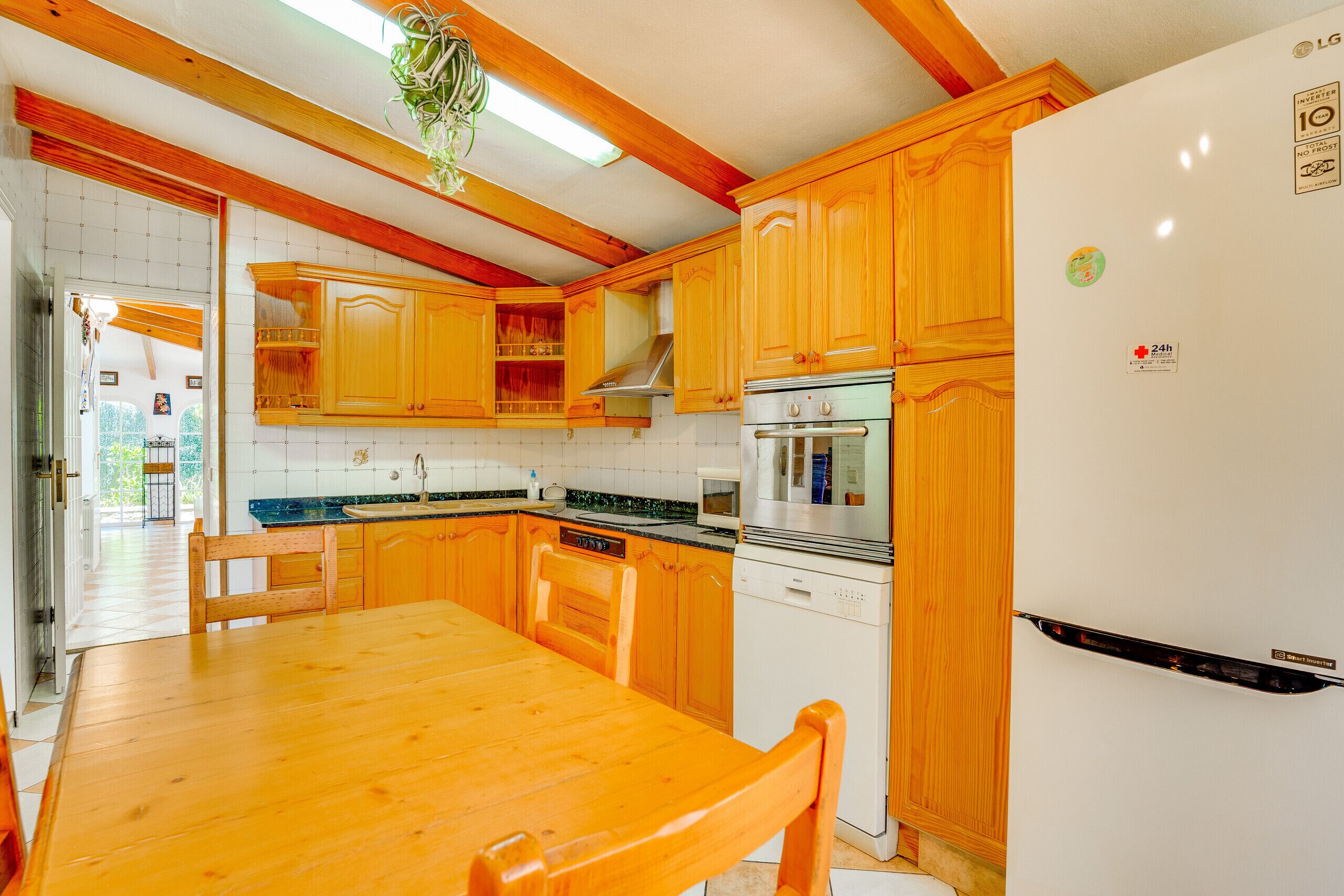 A kitchen with wooden cabinets, a stainless steel oven, a refrigerator, and a wooden dining table.