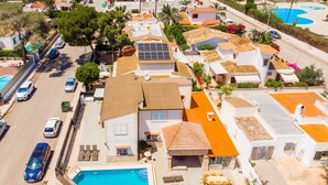 Vue aérienne d’un quartier résidentiel avec des maisons, une piscine et des voitures garées.