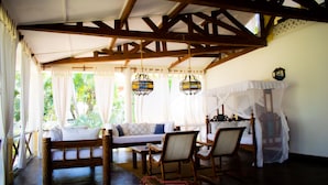 A room with a wooden ceiling, a bed with a canopy, a sofa, and two chairs. - Mambrui Villa (Malindi)