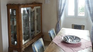 A dining area with a wooden table, chairs, a cabinet with glass doors, and a chandelier. - Apartment in old rectory with lake view, terrace and garden - 3 persons (Ghiffa)
