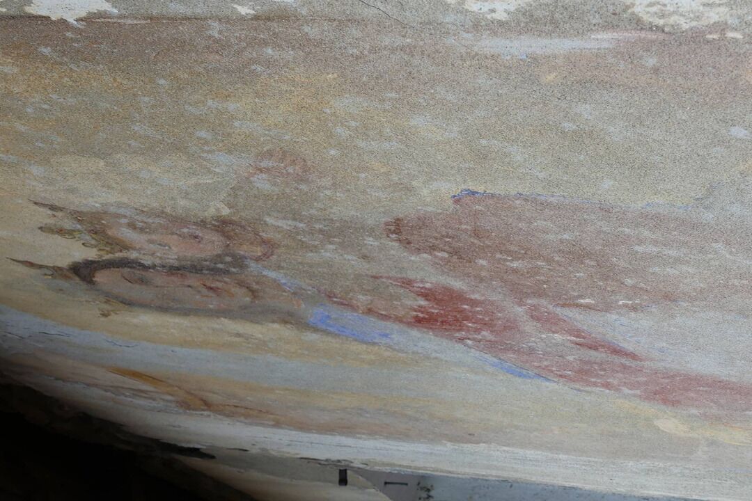 A close-up of a textured wall with peeling paint and visible damage.