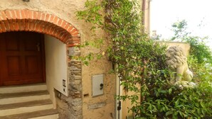 A stone building with a wooden door, a brick archway, and a lion statue. - Apartment in old rectory with lake view, terrace and garden - 3 persons (Ghiffa)