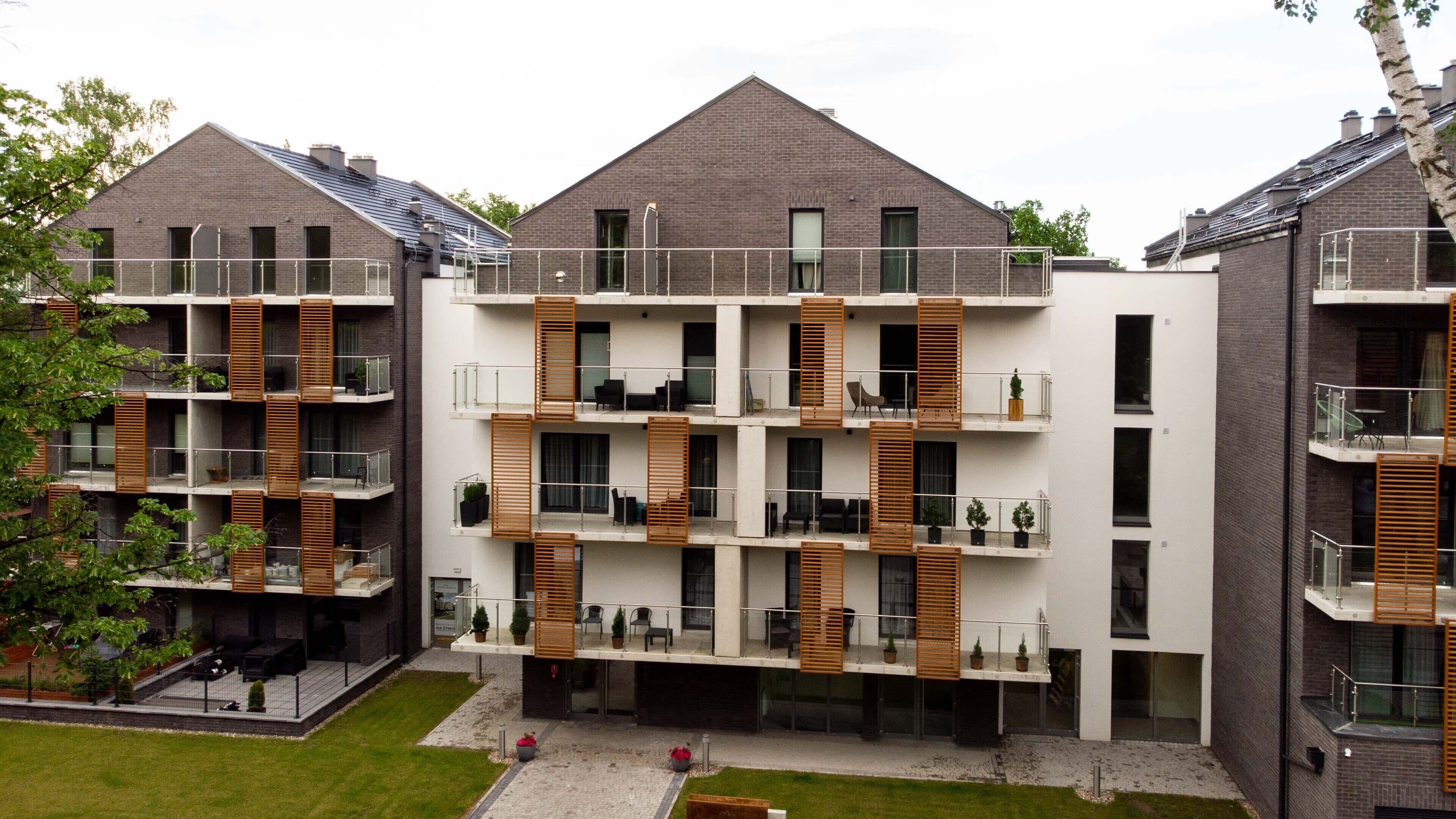 Ein modernes Mehrfamilienhaus mit Balkonen, Innenhof und Ziegel Fassade.