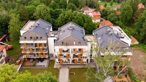 Un immeuble d’appartements moderne doté de nombreux balcons, d’une cour intérieure et entouré d’un paysage verdoyant luxuriant.