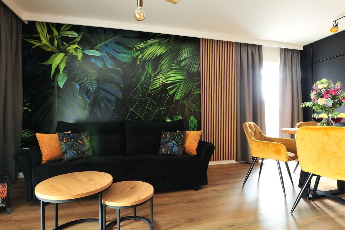 Una sala de estar moderna con un sofá negro, sillas amarillas y una mesa de centro de madera.