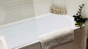 A bathroom with a bathtub, a towel, and a small potted plant.