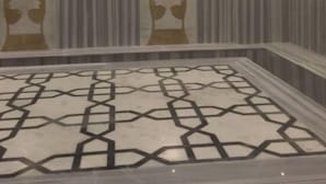 A room with a patterned floor, a ceiling with recessed lighting, and a wall with vertical stripes and two decorative elements. - Mostar Hotel (Antalya)
