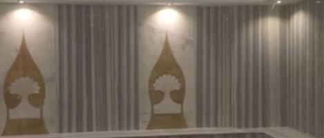 Una habitación con suelo estampado, techo con iluminación empotrada y pared a rayas verticales con dos elementos decorativos.