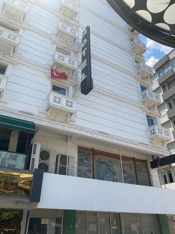 A multi-story hotel with a prominent sign, balconies, and air conditioning units.