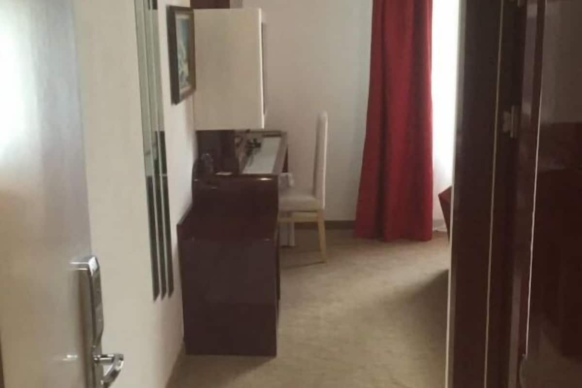A hallway leading to a room with a desk, chair, and a red curtain.