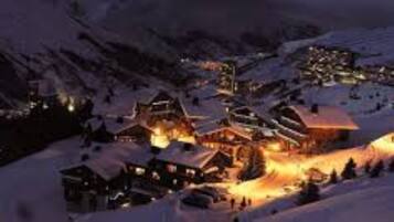 Un village enneigé, dont les bâtiments sont illuminés la nuit.
