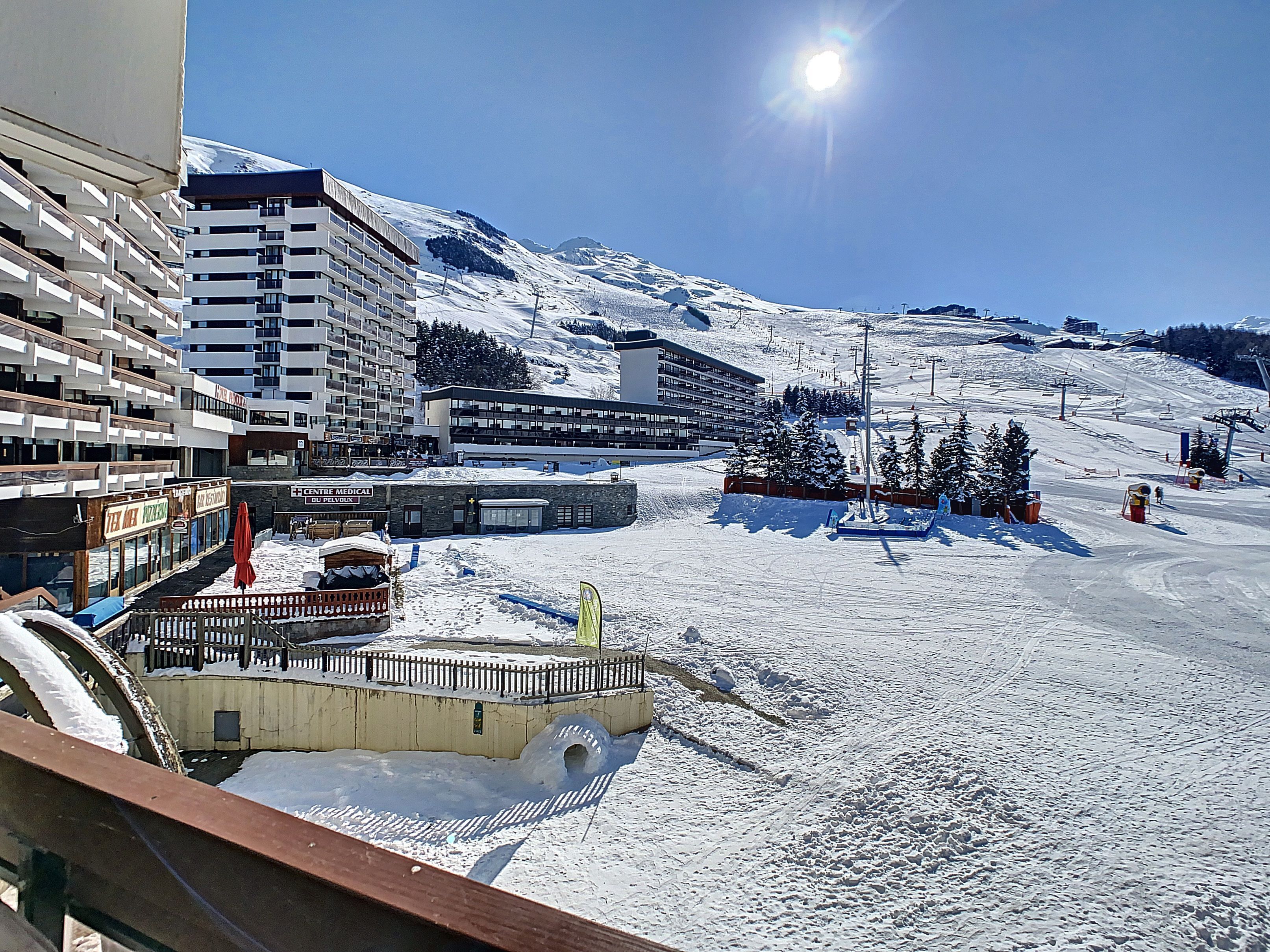 Un hotel con diversi piani, una seggiovia e una montagna innevata sullo sfondo.