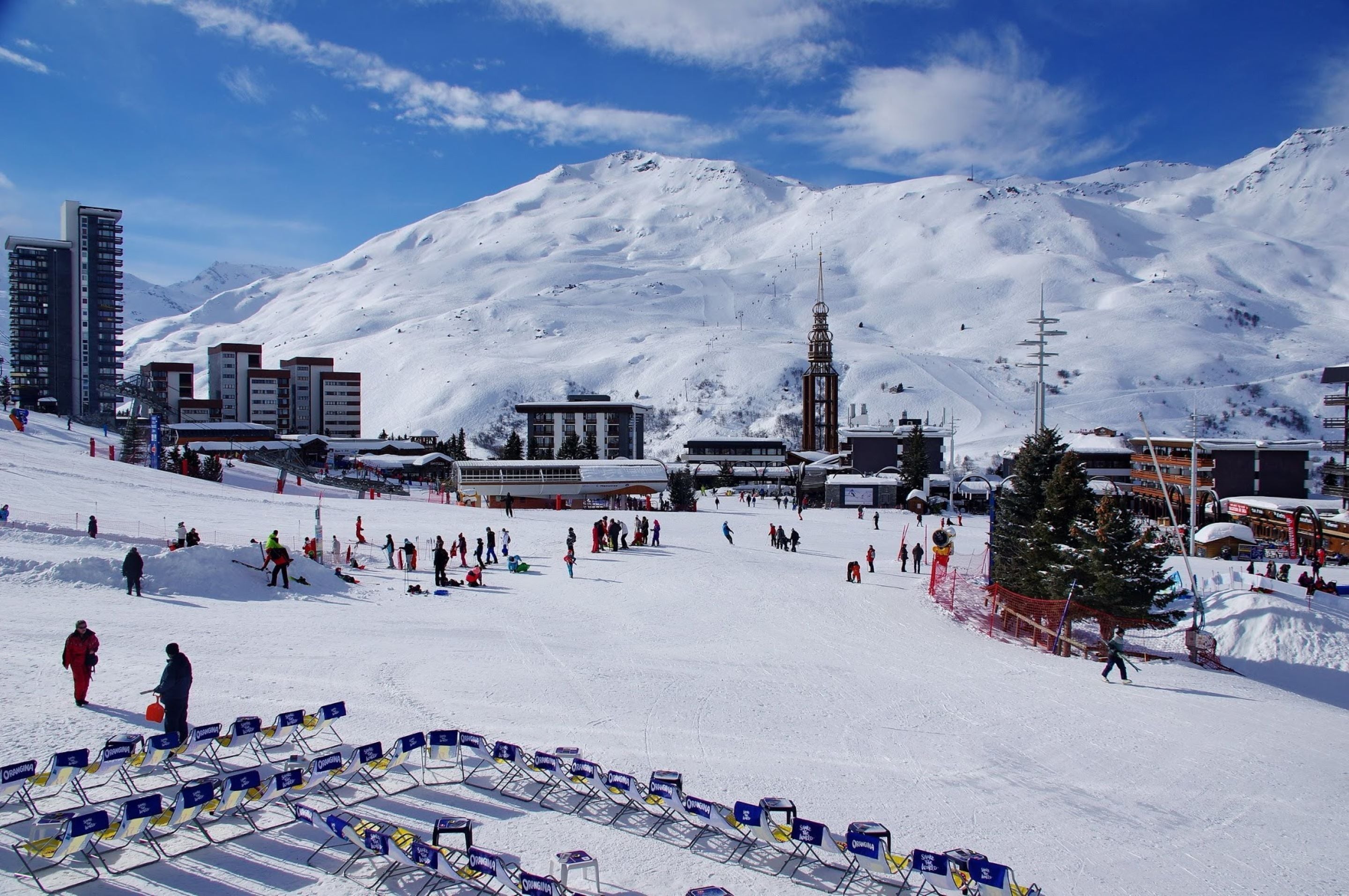 A ski resort with snow-covered slopes, buildings, and a mountain backdrop.