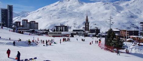 A ski resort with snow-covered slopes, buildings, and a mountain backdrop.