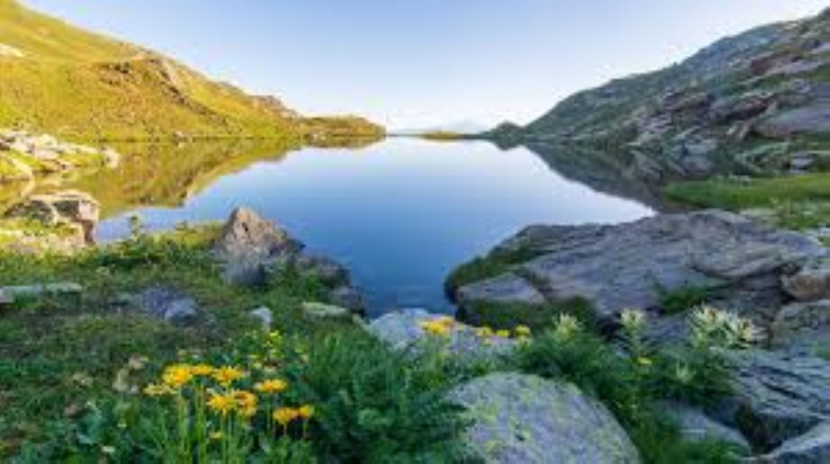 A serene lake surrounded by rocky terrain and lush greenery.